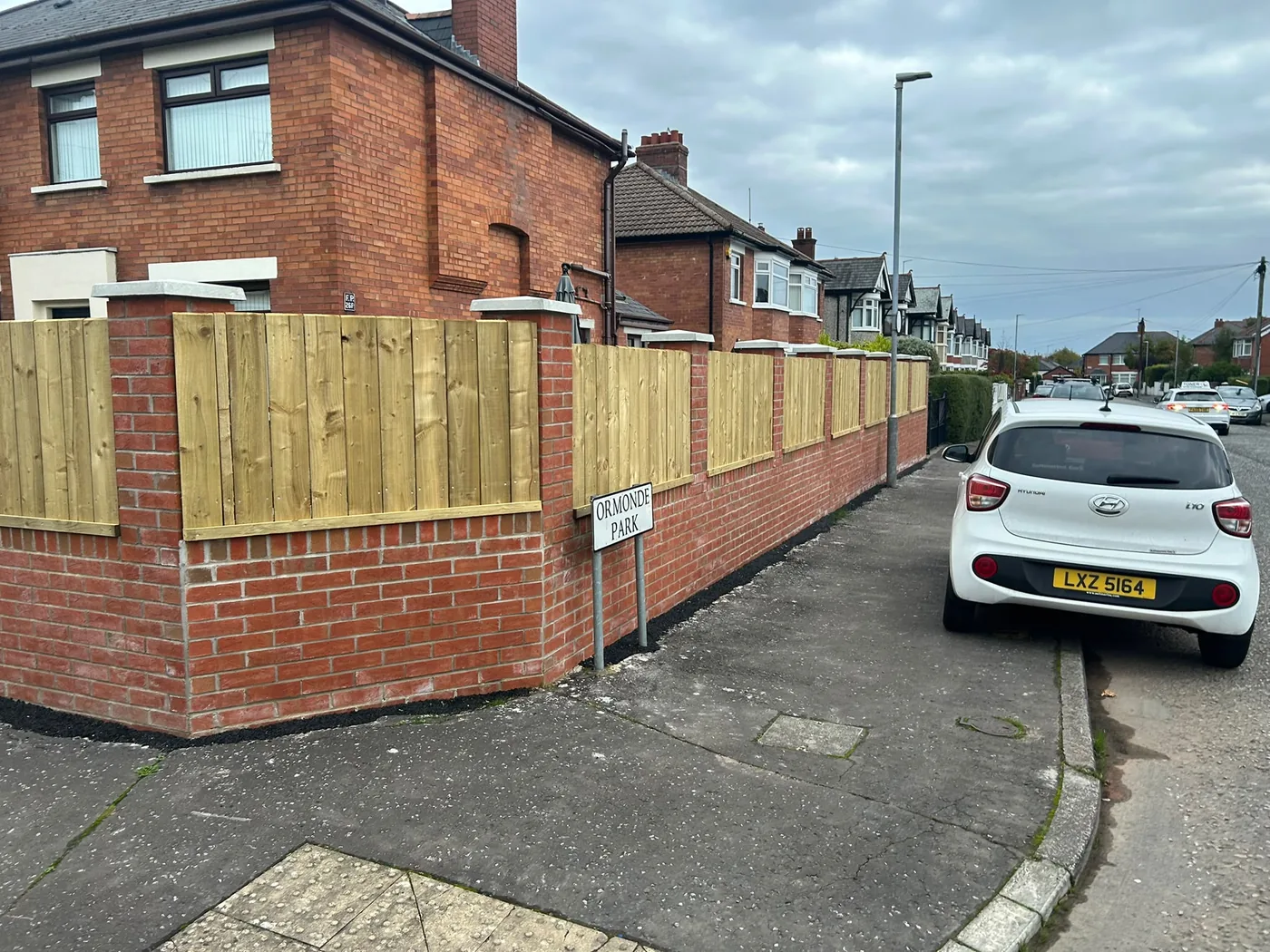 Rebuilt red brick boundary wall and pillars, finished with timber panels and pale coping