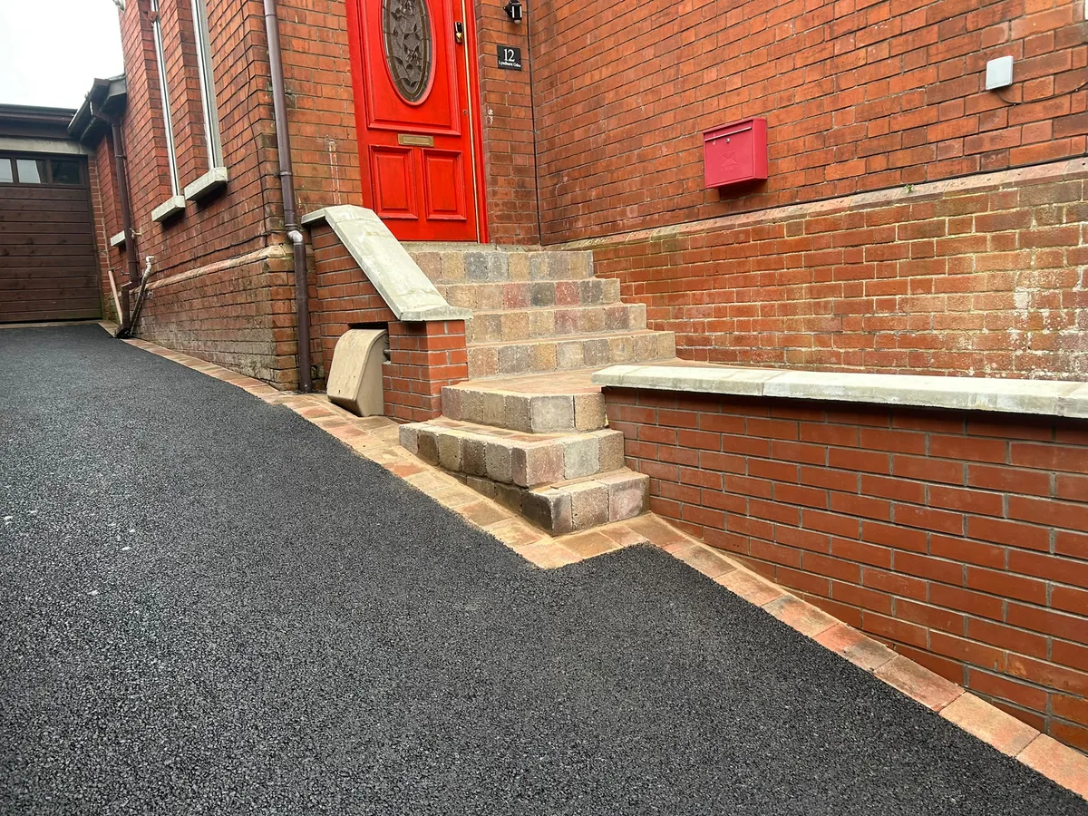 Paved entrance steps framed by brick walls with pale coping and a border beside the driveway